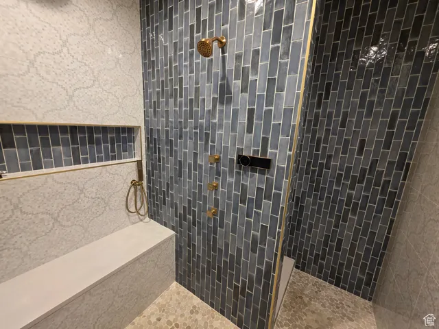 Bathroom featuring tiled shower and tile walls