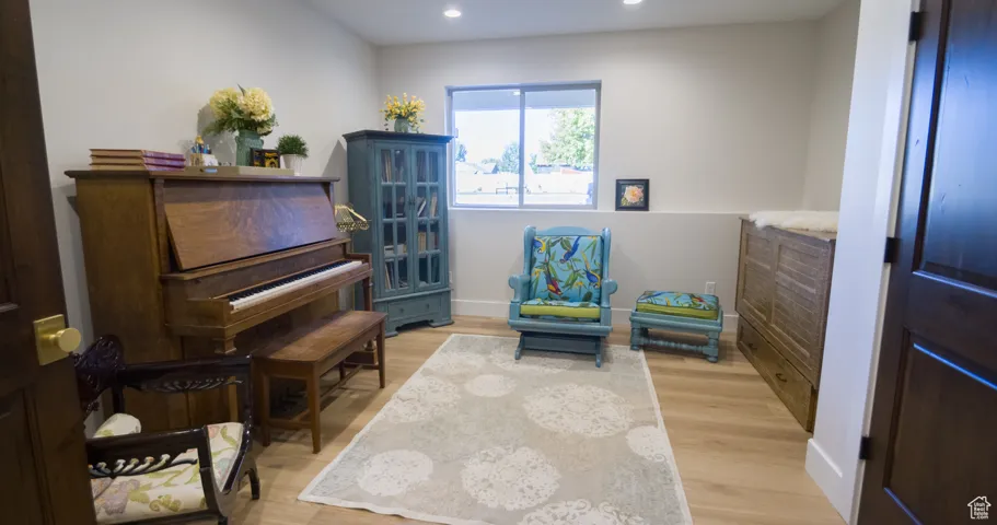 Sitting room with light wood finished floors and recessed lighting