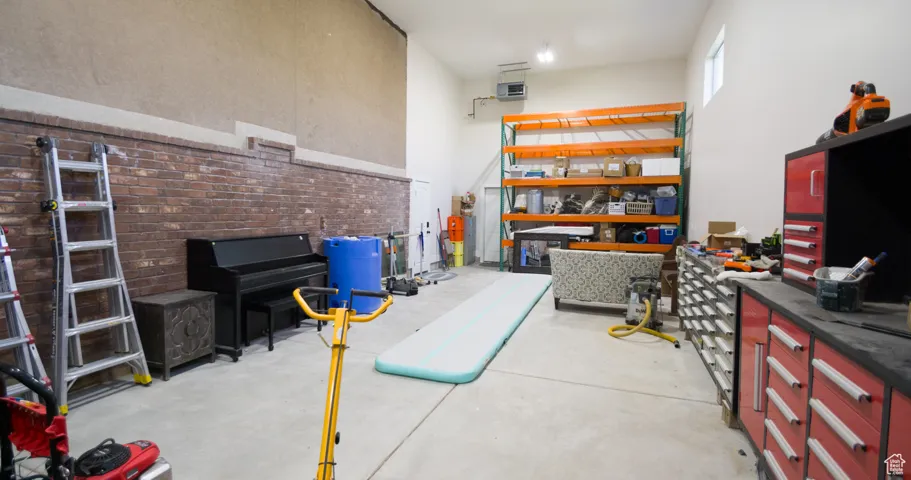 Miscellaneous room with a high ceiling, concrete flooring, and a heating unit