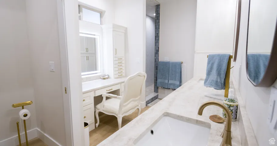 Full bath with double vanity and light wood-style flooring
