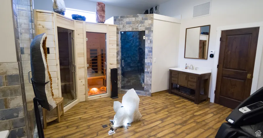 Bathroom with vanity, a sauna / steam room, a stall shower, and wood finished floors