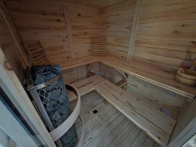 Relaxing sauna / steam room with wooden walls, hardwood / wood-style flooring, and wooden ceiling
