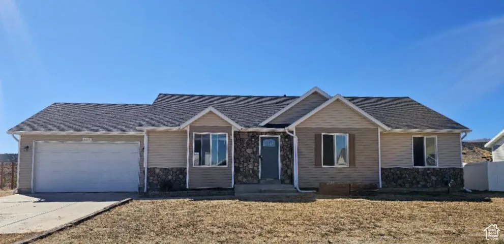 View of front facade with stone siding, a garage, and concrete driveway