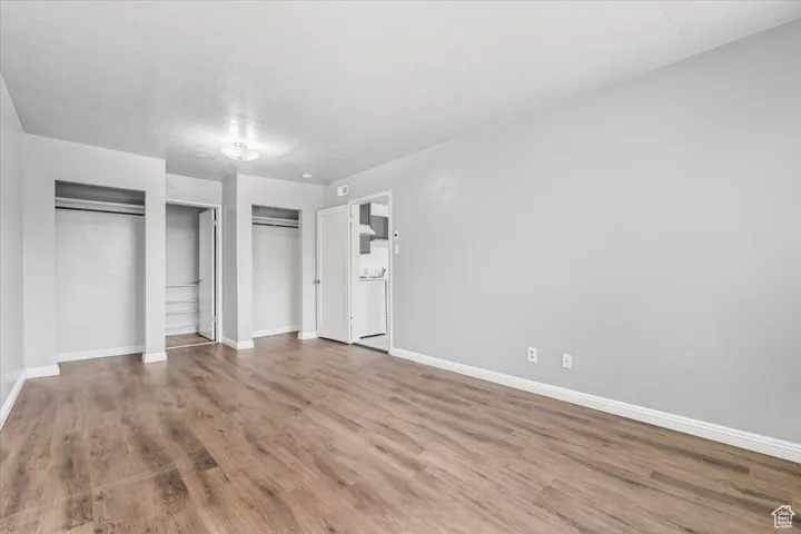 2 BR/2 BA Apartment Unfurnished bedroom featuring multiple closets, wood finished floors, and a textured ceiling