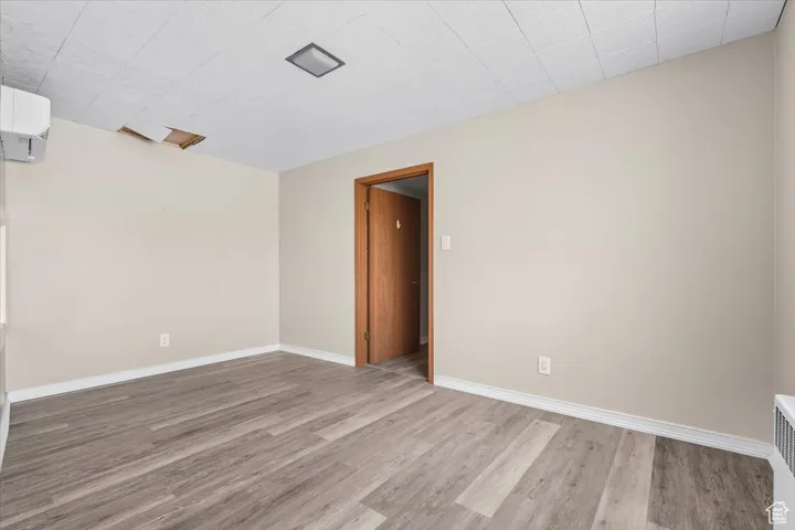 Spare room featuring light wood-style floors, a wall mounted AC, and radiator heating unit