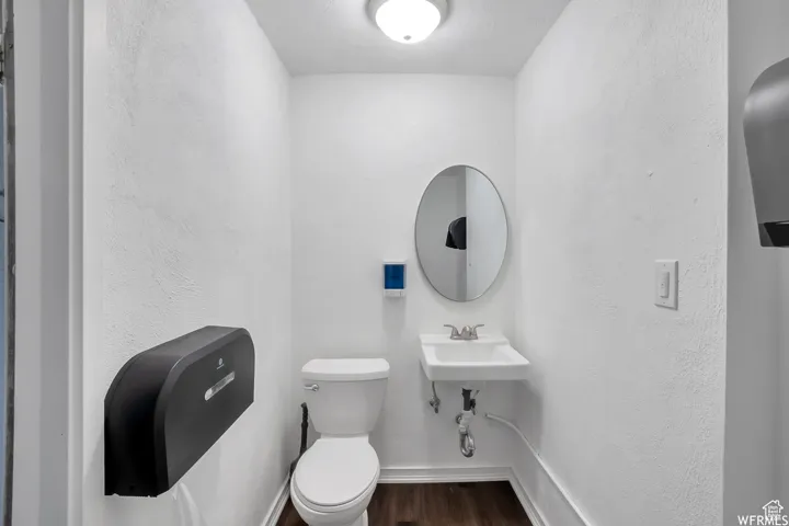 Bathroom featuring a textured wall and dark wood finished floors