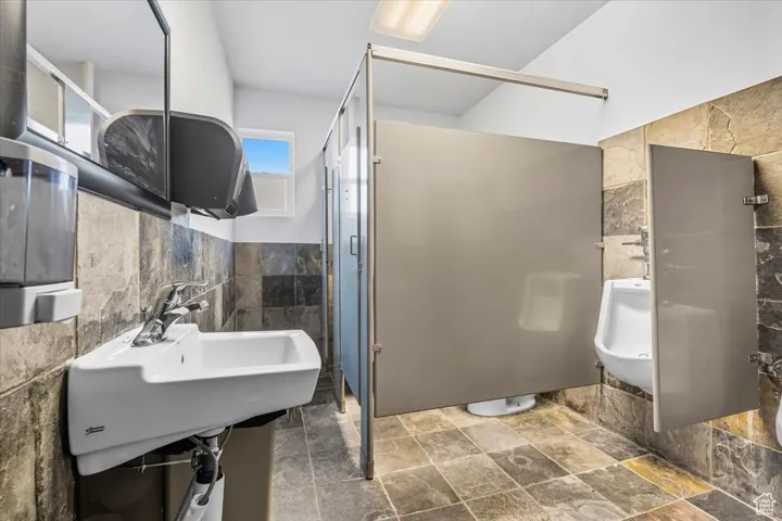 Bathroom with tile walls, stone finish flooring, and a wainscoted wall
