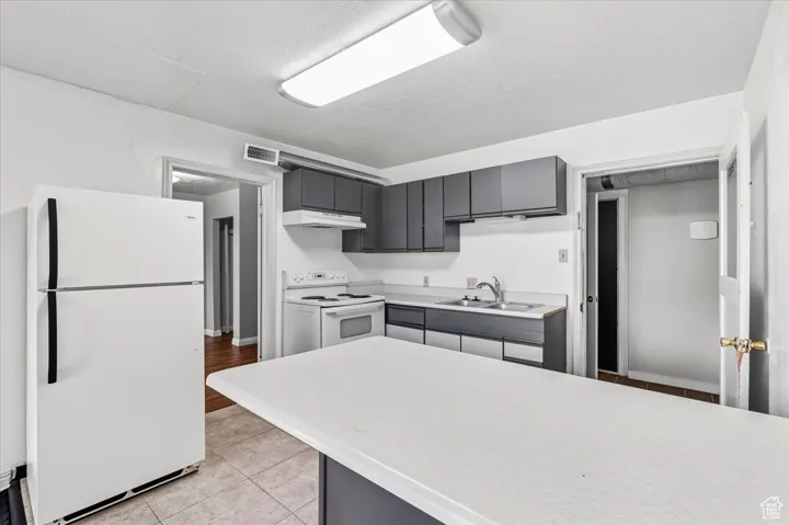 2 BR/2 BA Apartment Kitchen with gray cabinetry, white appliances, light countertops, light tile patterned floors, and under cabinet range hood