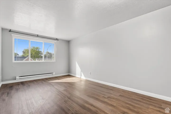 2 BR/2 BA Apartment featuring a baseboard radiator, wood finished floors, and a textured ceiling