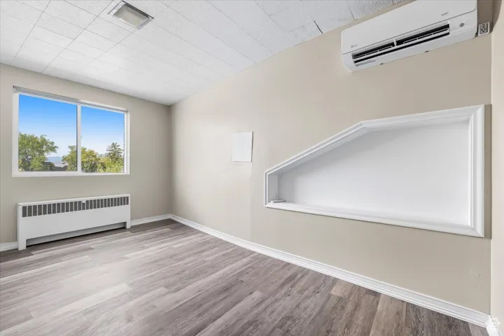 Spare room with radiator, a wall mounted air conditioner, and light wood-type flooring