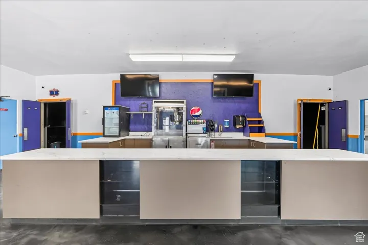 Theater Lobby featuring fridge and light stone countertops