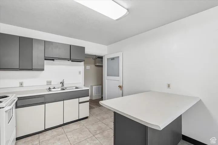 Kitchen featuring a peninsula, light countertops, light tile patterned floors, a kitchen breakfast bar, and gray cabinets