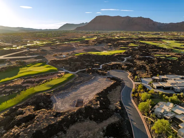 Golf course frontage with undulating green fairways, surrounded by natural rock formations and a paved roadway