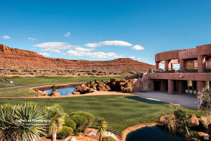View of green lawn with view of golf course, a water and mountain view, a patio, and a balcony