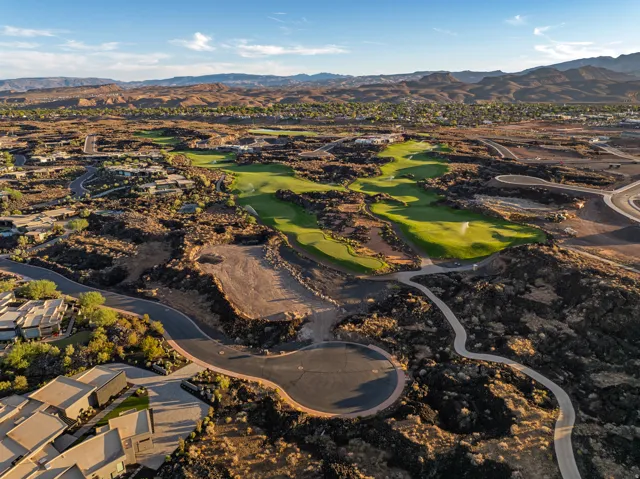 Aerial landscape featuring a manicured golf course, surrounding residential properties, paved roads, and natural rock formations