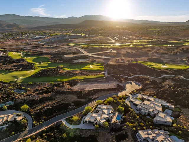Aerial perspective showcasing a residential development with golf course access, surrounding mountains, and a community with curved roadways