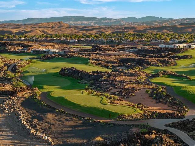 Expansive golf course setting featuring manicured greens, natural rock formations, and distant mountain scenery