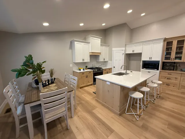 Kitchen with a kitchen bar, glass insert cabinets, decorative backsplash, stainless steel range with gas stovetop, and recessed lighting