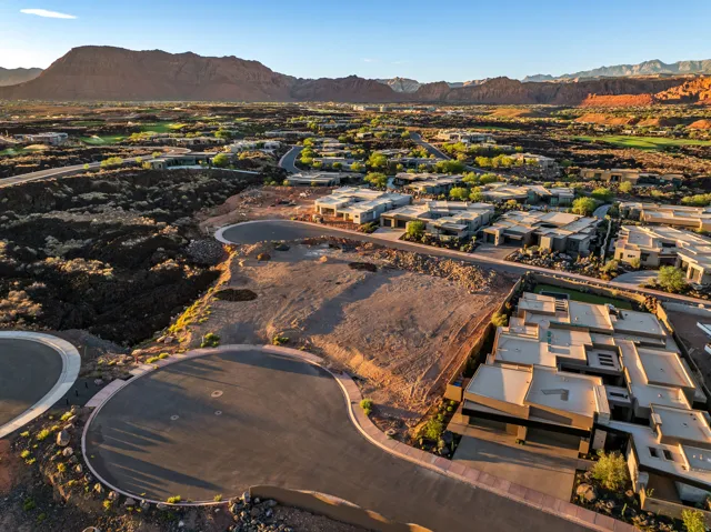 Expansive undeveloped lot with surrounding residential properties, paved streets, and mountainous desert landscape