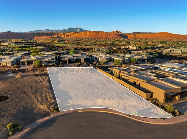Expansive lot with a curved road frontage, surrounded by modern residences, and featuring distant mountainous scenery