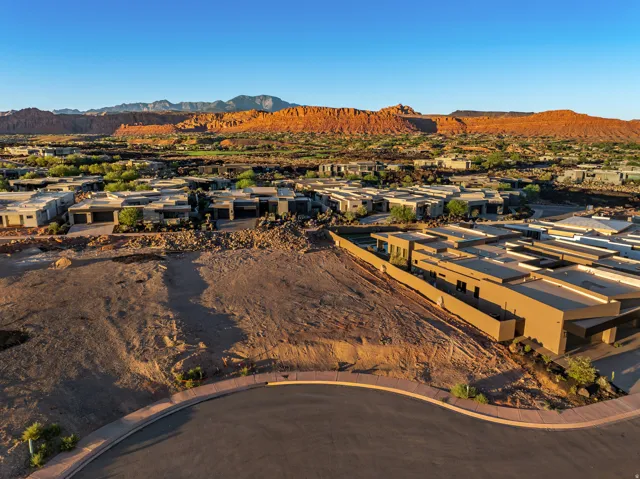 Expansive undeveloped lot with street frontage, surrounded by modern residences and natural rock formations