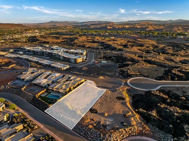 Expansive undeveloped land parcel with surrounding paved roadways and distant mountain scenery