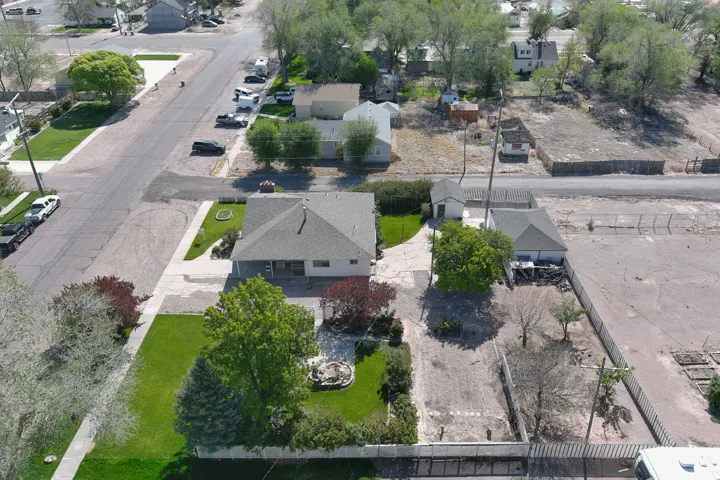 Aerial perspective showcasing a single-story residence with a gray shingle roof, accompanied by an additional detached structure