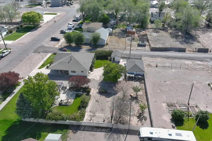 Aerial perspective showcasing a single-story residence with an attached covered porch and a detached garage structure