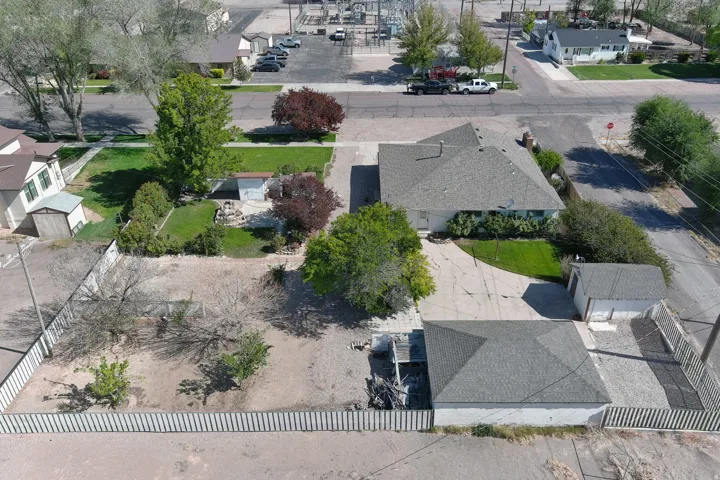 Property featuring a single-story residence with a gray shingle roof, a detached garage, an additional storage shed, a fenced backyard, and a paved driveway