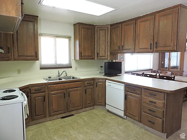 Kitchen featuring a peninsula, light countertops, and white appliances