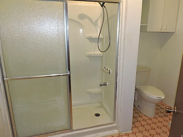 Bathroom with a shower stall and light tile patterned floors