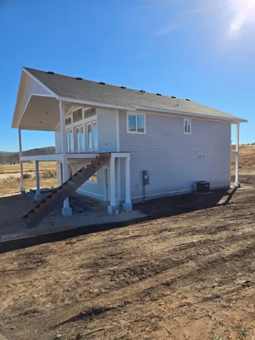 Back of house with stairs and roof with shingles