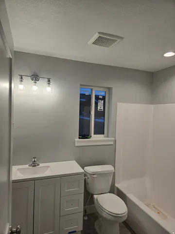 Full bath with vanity, a textured ceiling, and  shower combination