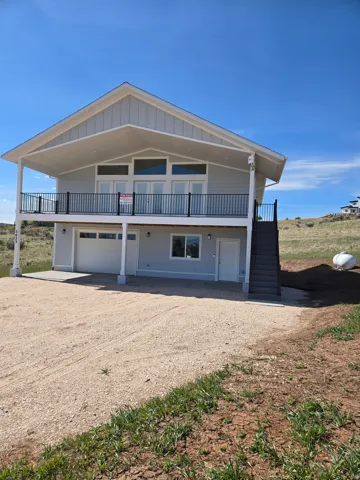 View of front of home with dirt driveway, covered porch, a garage, and board and batten siding