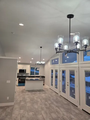 Kitchen featuring a chandelier, pendant lighting, recessed lighting, a center island, and white cabinets