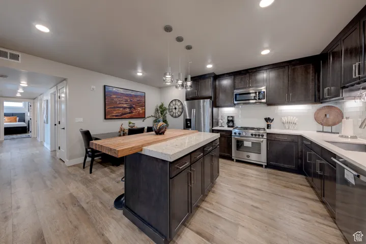 Kitchen featuring backsplash, dark brown cabinetry, a kitchen island, stainless steel appliances, and recessed lighting