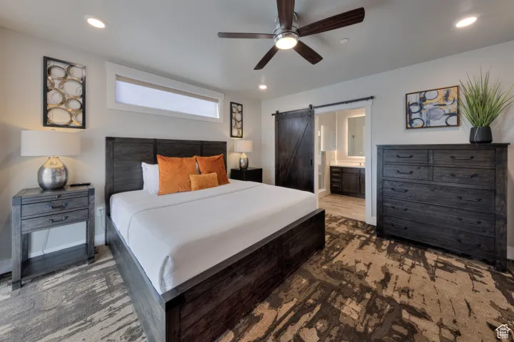 Bedroom with recessed lighting, a barn door, ceiling fan, and ensuite bath