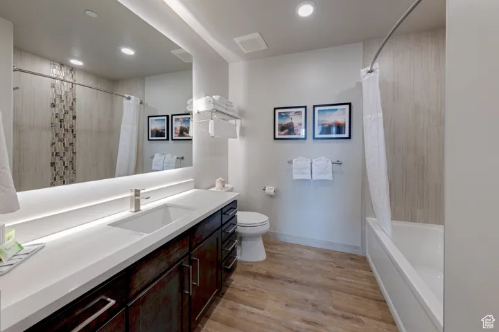 Bathroom with vanity, shower / bath combination with curtain, light wood-style flooring, and recessed lighting
