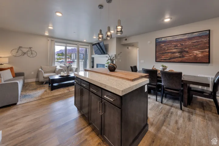 Kitchen featuring dark brown cabinets, open floor plan, decorative light fixtures, a center island, and dark wood-style floors