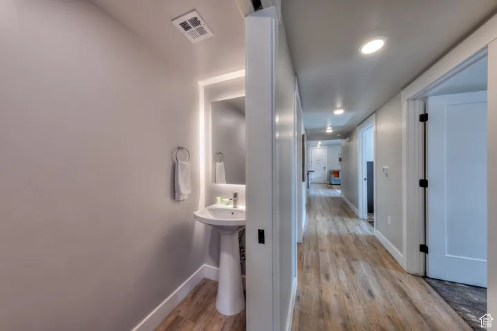 Corridor with light wood-style flooring and recessed lighting