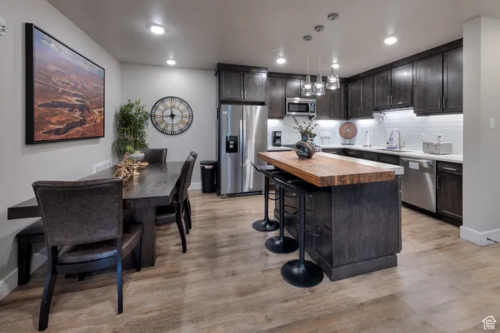 Kitchen with butcher block counters, decorative backsplash, stainless steel appliances, a kitchen breakfast bar, and a kitchen island
