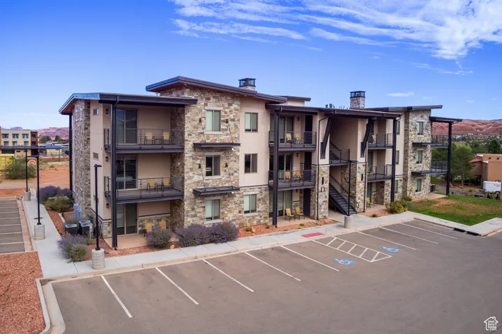View of building exterior with uncovered parking and stairs