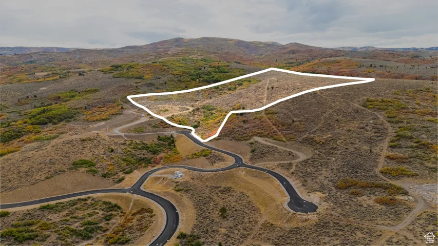 Aerial view of property and surrounding area with property parcel outlined and a mountainous background