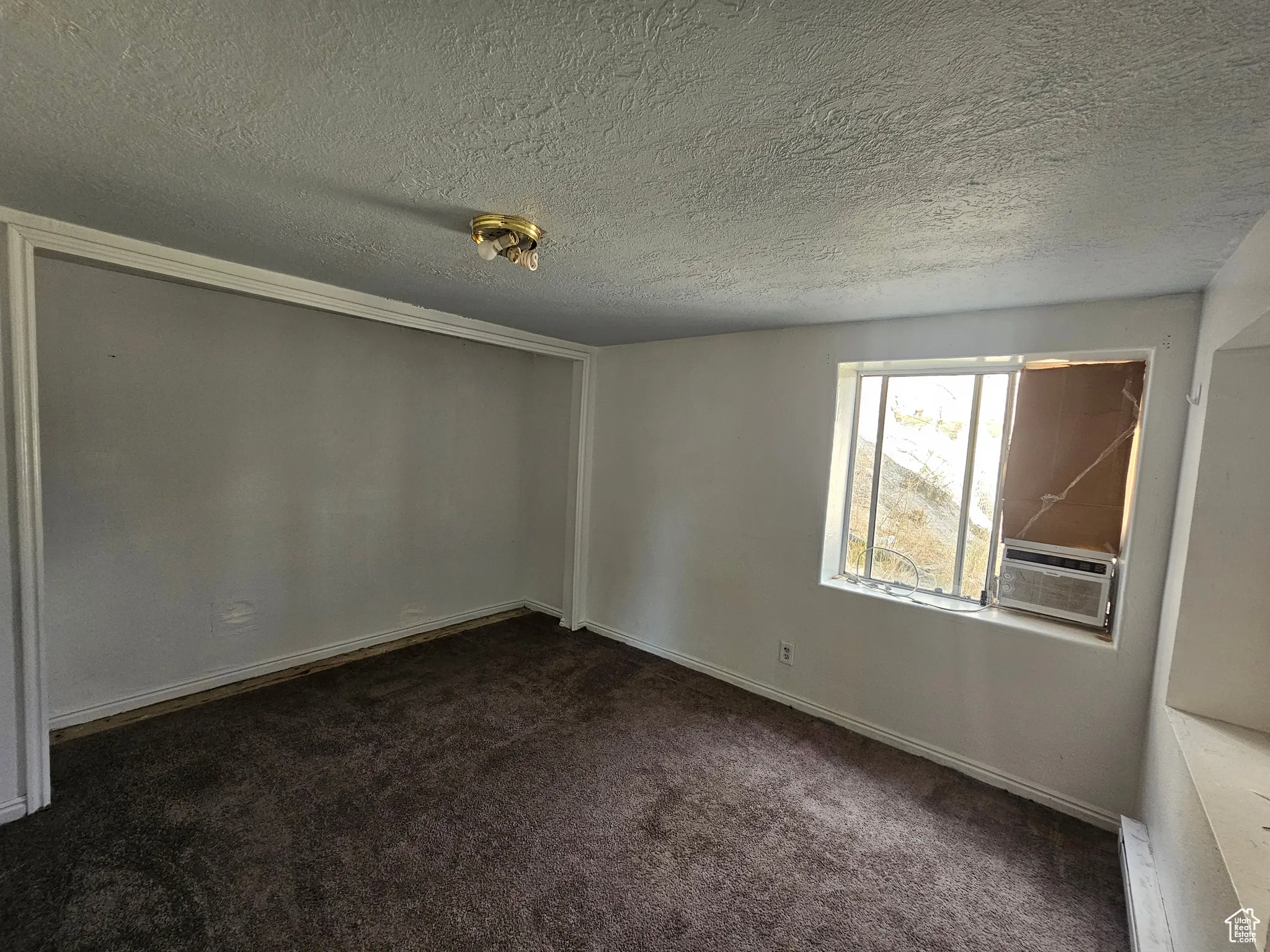 Spare room featuring dark carpet, a textured ceiling, and a baseboard heating unit