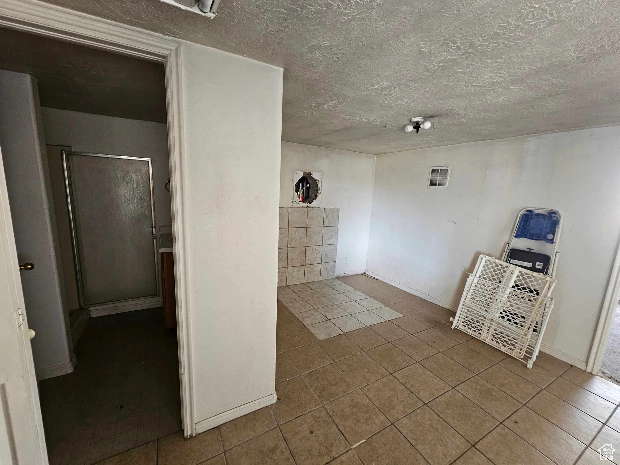 Tiled spare room with baseboards and a textured ceiling
