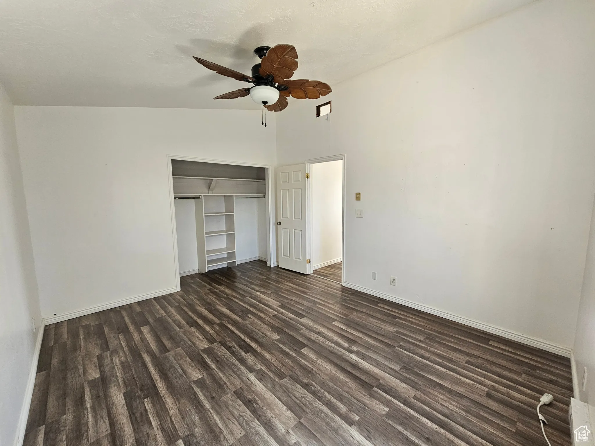 Unfurnished bedroom with a closet, dark wood-type flooring, a ceiling fan, lofted ceiling, and a textured ceiling