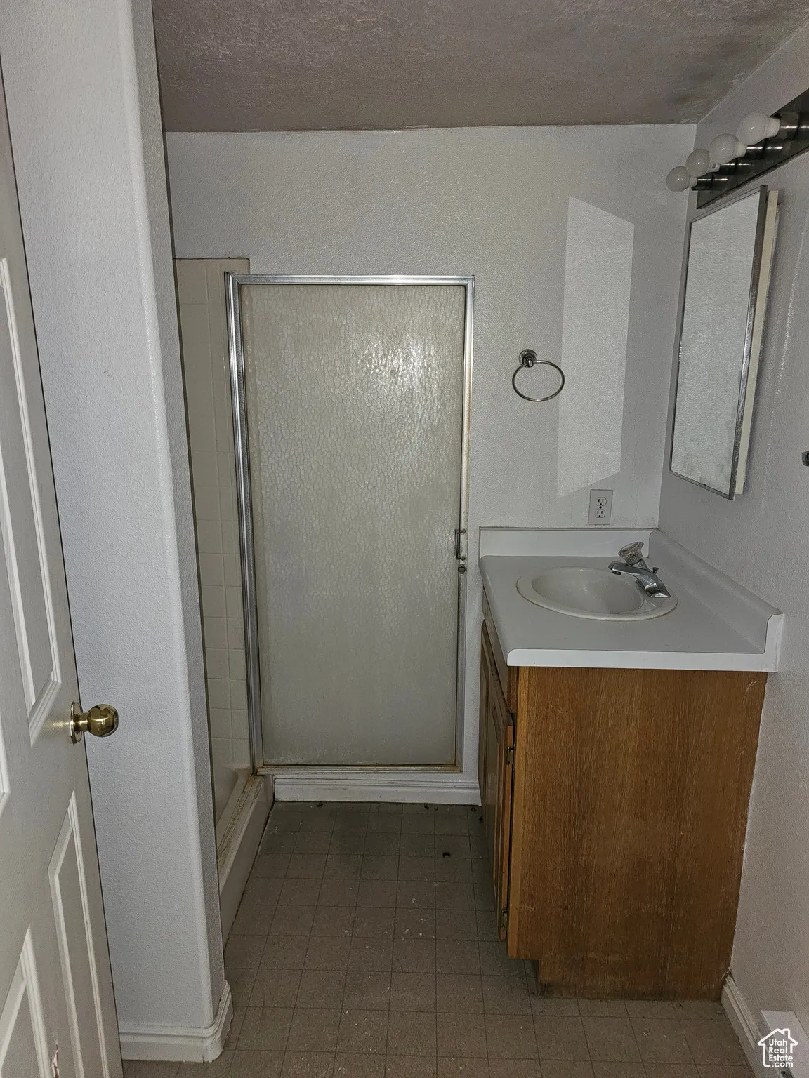 Bathroom with a stall shower, vanity, and a textured wall