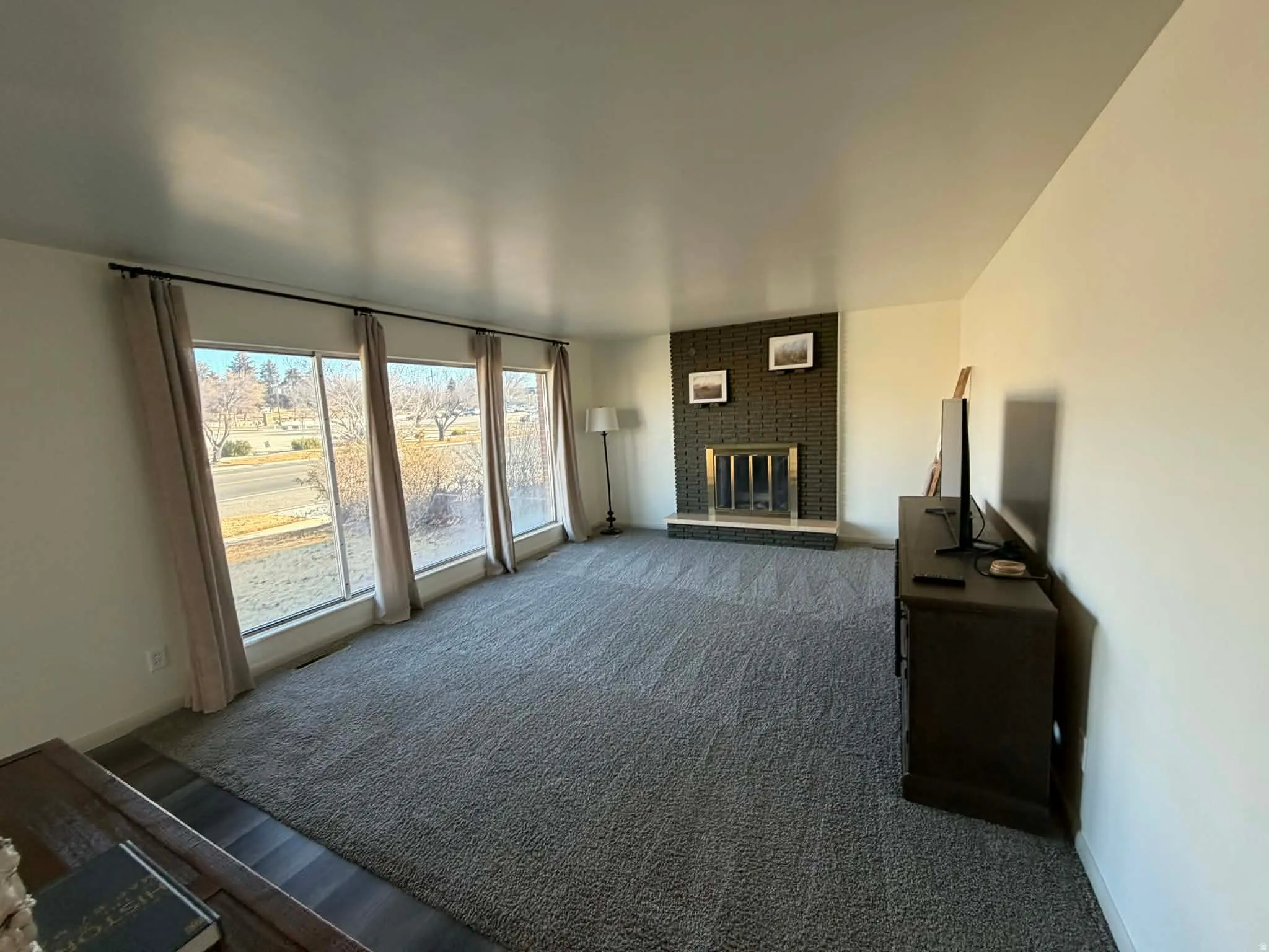 Unfurnished living room with a fireplace and dark carpet