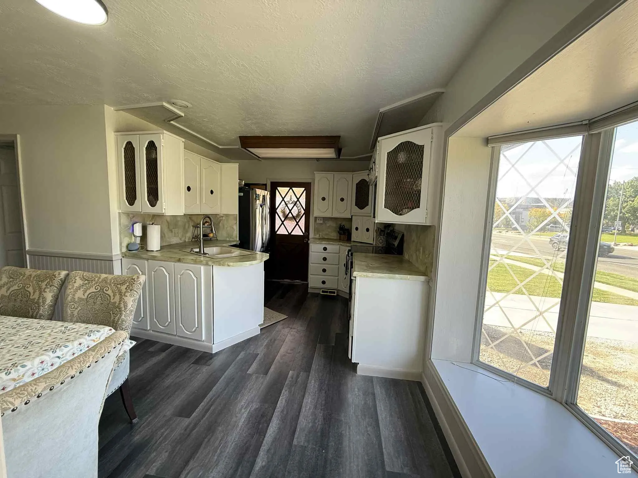 Kitchen featuring all new appliances as of 2024, white cabinetry, a textured ceiling, light countertops, dark wood-style floors, and white range oven and front window seat