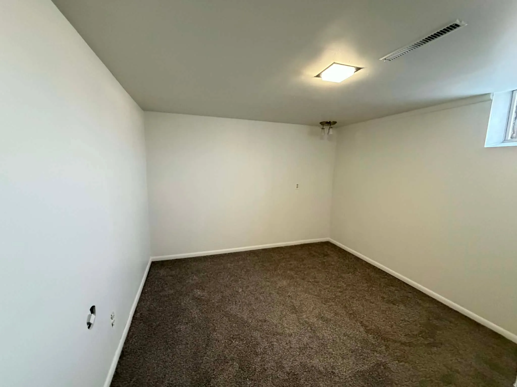 Empty room featuring dark carpet and baseboards
